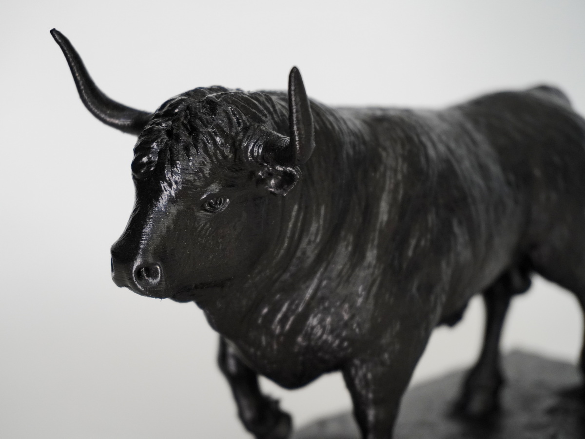 Black bull sculpture with a satin black finish, close-up view showing the horns, head, and textured surface